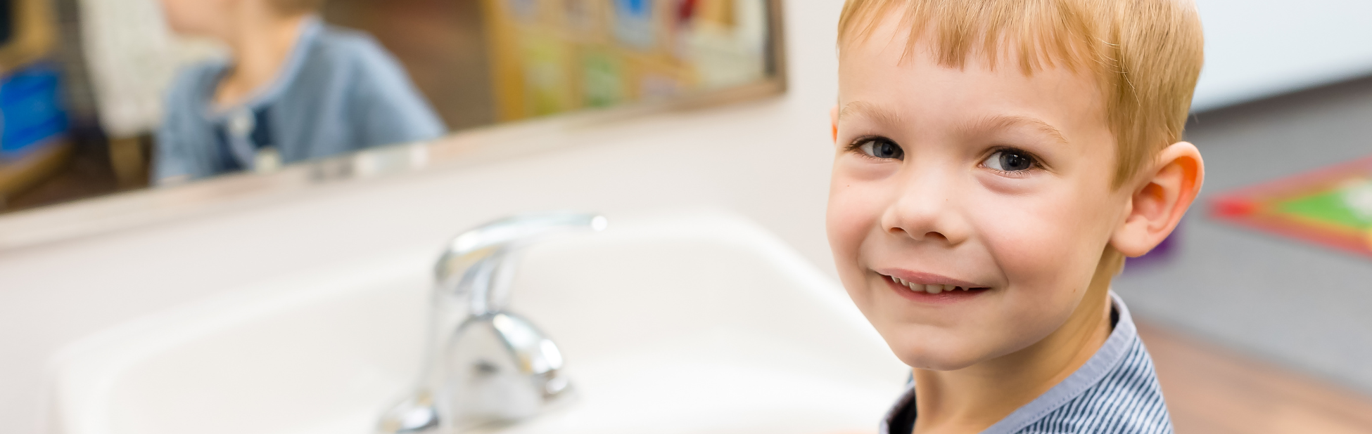 kid standing by sink washing hands